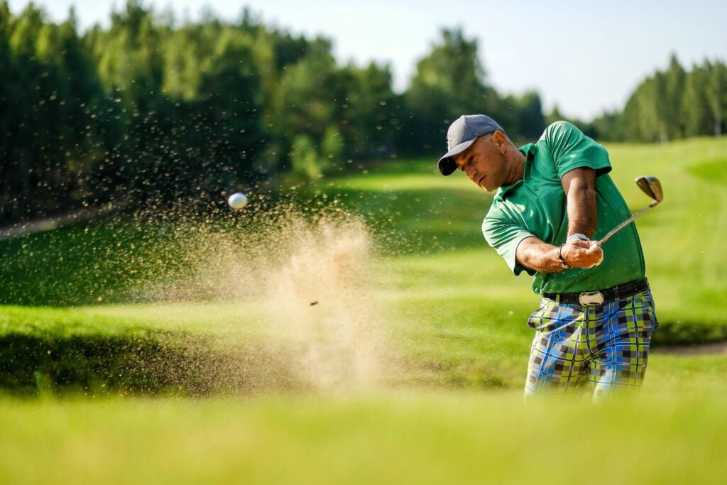 Whats the one thing golfers can do with bunkers to make life easier for greenkeepers? | National Club Golfer A golfer hits a shot from a bunker | Source: Adobe Stock
